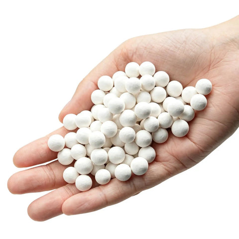 Hand holding 8 Pound Ceramic Tumbling Media Balls For Rock Tumblers Reusable White Alumina Pellets Three Tenths Inch Diameter Grit