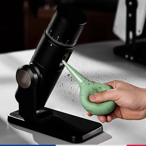 Hand using a green sparrow-inspired air blower on espresso machine, Dope Bird Inspired Coffee Air Blower Air Duster For Espresso Machines And Delicate Electronics Like Watches Cameras Keyboards And Sensors Removable Pump Cleaning Tool In White.