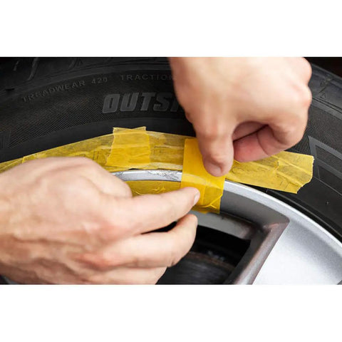 Applying tape to a black alloy wheel before using the Solid Alloy Wheel Repair Kit For Black Rims Smooths Out Curb Rash And Road Scuffs DIY.