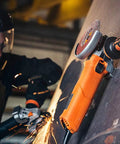 Grinder Grip Magnetic Attachment For Grinders Attaches To Ferrous Surfaces For Safer, Easier Pipefitting, Welding, Metal Fabrication, Automotive, And HVAC Work A Real Game Changer holding orange grinder on metal surface
