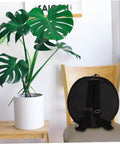 Premium Heavy Duty Waterproof Drum Instrument Backpack Featuring Rugged Adjustable Shoulder Straps And Smart Storage Layout For Weekend Musician Lifestyle on a chair next to a potted plant.