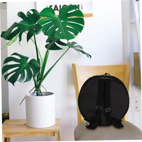Premium Heavy Duty Waterproof Drum Instrument Backpack Featuring Rugged Adjustable Shoulder Straps And Smart Storage Layout For Weekend Musician Lifestyle on a chair next to a potted plant.