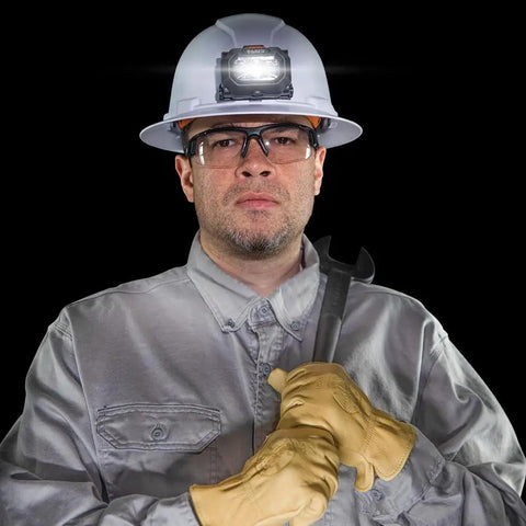 Intrinsically Safe LED IP67 Headlamp for Hazardous Areas attaches to hard hats, worn by worker with wrench and safety gear.