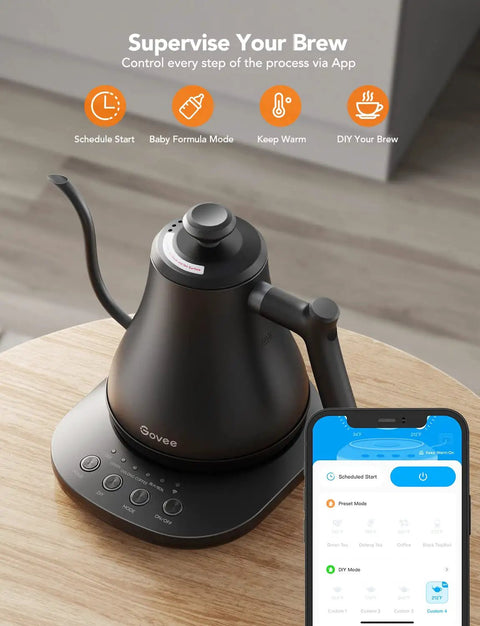 Smart Electric Kettle With WiFi And Alexa Control For Home Baristas Gooseneck Pour Over Kettle With Variable Temperature 1200W Quick Heat 0.8L Capacity One Hundred Percent Stainless Steel Matte Black on wooden table next to smartphone displaying control app.