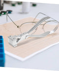 Eyeglass Adjustment Pliers for Nose Pad Screws Quick Fix Tool placed on sheet with eyeglasses in background