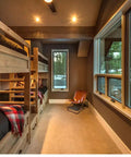 Cozy bedroom with bunk beds and natural light, featuring wood accents and a rustic atmosphere.