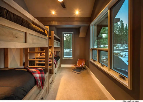 Cozy bedroom with bunk beds and natural light, featuring wood accents and a rustic atmosphere.
