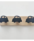 Slick Wall Mounted Coat Hooks With Dope Car And Crown Cuts Super Chill Nursery Decor Zero Stress Solution For Sweaters Beanie Hats Fleece Wraps And Bath Towels In The Little Kids Room Today with three black car hooks on wood board.