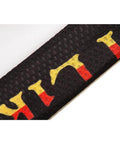 Close-up of black textured fabric with yellow and red letter pattern, highlighting detail.