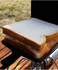 Sandwich cooking in Cast Iron Camp Pie Cooker Set Of 2 For Campfire Sandwiches And Pies, pre-seasoned square pie iron on open flame.