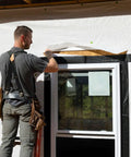 Worker installing Pro Grade Flashing Tape For Windows And Doors, 3.75 Inch Wide, 30 Foot Roll, all-weather, black, around window