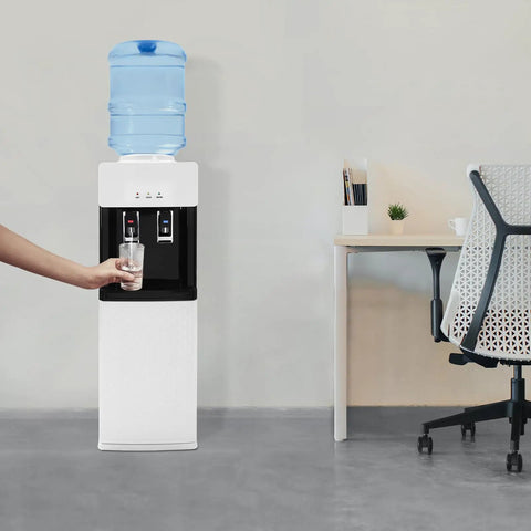 Person using hot and cold water dispenser with five gallon top loading electric heater and cooler next to office desk