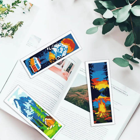 Camping Theme DIY Cross Stitch Bookmark Kit For Beginners, 6 Pack With Mountain View Motifs displayed on an open book
