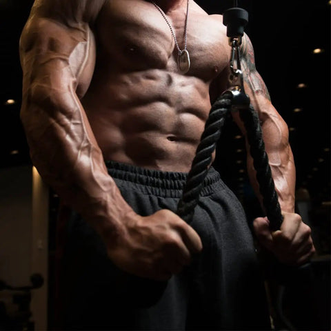 Man using cable attachments for gym lat pulldown machine, showing tricep rope workout with rugged knurl grip.