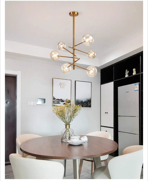 Modern Glass Pendant Lights Matte Gold Finish Six Or Eight Bulb Ceiling Fixtures hanging over a round table with chairs.