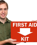 First Aid Kit Sign With Down Arrow 10 By 14 Inches Durable Plastic HDPE 55 Mil Weatherproof Indoor Outdoor Safety Sign Pre Punched Mounting Holes And Clear Arrow Lead For Easy Installation displayed by person