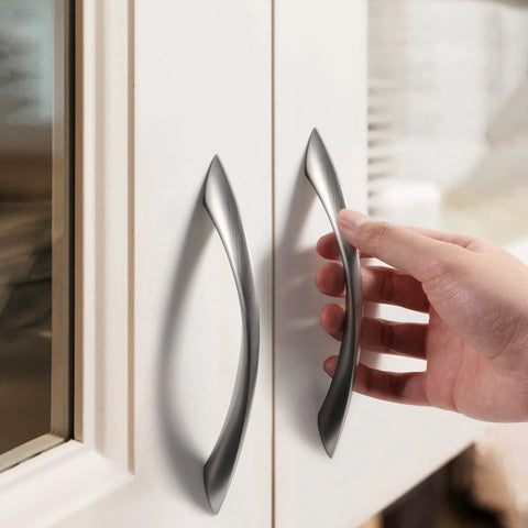 Hand installing a 10 Pack Brushed Nickel Cabinet Pulls 5 Inch Arch Twisted Silver Handles for drawers in a modern kitchen