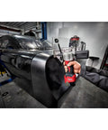 Milwaukee M12 Cordless Rivet Tool Bare Unit in use, fastening rivets on a black car body, showcasing compact design.