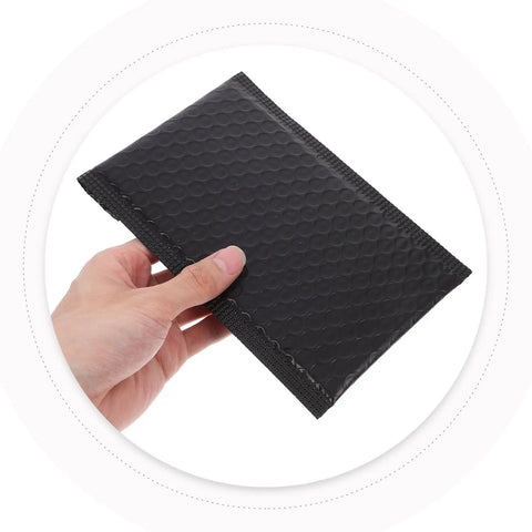 Hand holding Black Padded Bubble Mailer Envelopes 12x18, showcasing texture and size for small business shipping and jewelry protection.