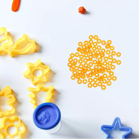 100 Pack Miniature Plastic Bushings and Axle Sleeves for Toy Vehicles on a table with craft tools.