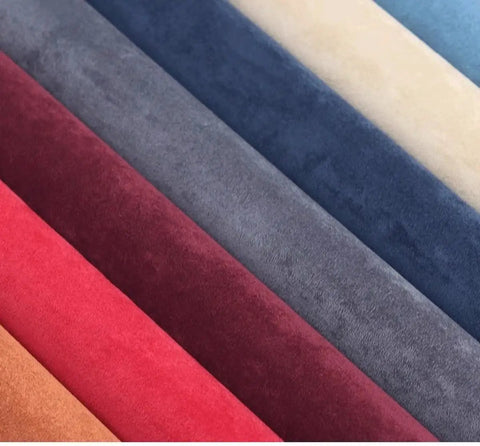 Colorful suede fabric rolls including red, grey, blue, and beige, showcasing textured upholstery material.