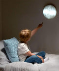 A child pointing at the Moon In My Room Light Up Lunar Phases Kit on wall, showcasing realistic moon details, ideal for learning lunar phases.