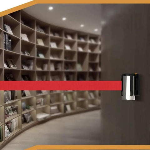 Heavy Duty Wall Mounted Retractable Belt Barrier With Magnetic Snap And Nine Foot Red Stanchion Rope for crowd control in library setting.