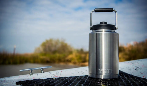 Rambler Gallon Water Jug With Vacuum Insulated Stainless Steel No Sweat Design MagCap Magnetic Lid on a dock outdoors
