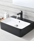 Matte Black Vessel Sink And Faucet Combo For Modern Bathrooms 18x16 Inch Rectangular Above Counter Porcelain Ceramic Vanity Sink With Dual Faucets Pop Up Drain And Water Lines installed on white countertop with water running.