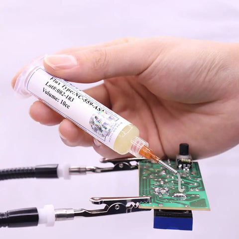 Hand using No Clean Flux Gel Paste for Soldering with Needle Dispensing Tool 559 ASM on electronic circuit board
