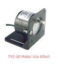 Mini gear motor with mounting bracket, gray metal housing on a black L-bracket, side view