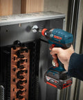 Impact Tough Quick Change Bit Holder For 2 Inch Bits Built To Last With Secure Fit Heat Treated Durability High Visibility Sleeve Boss Level Performance For High Torque Impact Drivers 10x Life Vs Standard Bits attached to an impact driver securing a bolt in an electrical panel.