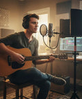 Young man playing acoustic guitar with a 6 Panel Microphone Isolation Shield With Adjustable Metal Stand For Podcast Recording Studio Vocal Booth Sound Deadening Screen.
