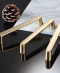 Brushed Brass Cabinet Pulls 7 Inch Length 6.3 Inch Center To Center Gold Handles on black surface with pine cone