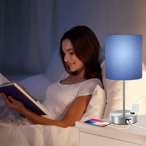 Woman reading beside Touch Control Table Lamp Blue Shade Three Way Dimmable Lamp With Two Fast Charging USB Ports And Power Outlet Bedside Nightstand Lamp For Bedroom Living Room Daylight White Bulb Included illuminating the room.