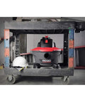 6 Gallon Wet Dry Shop Vacuum With Casters 4.25 Peak HP Motor in garage under workstation with a hard hat nearby