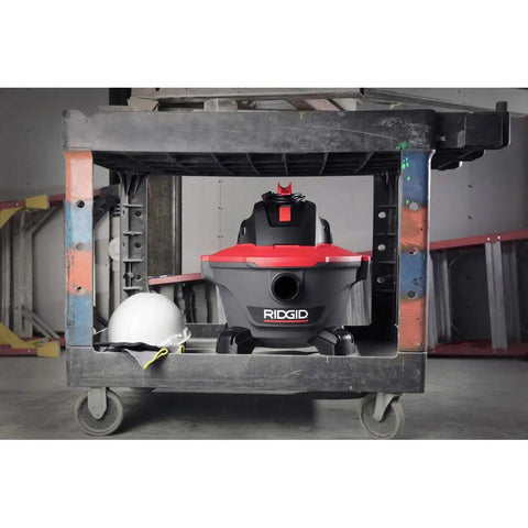 6 Gallon Wet Dry Shop Vacuum With Casters 4.25 Peak HP Motor in garage under workstation with a hard hat nearby