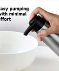 Person using Stainless Steel Liquid Soap Dispenser 15 Fl Oz For Dish And Hand Soap No Fuss Pump Top Lifts Off For Easy Refill near bowl