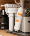 Pack Of Three 10 Inch Inline Resin Filters With Quarter Inch Quick Connect seen installed near coffee machine for hard water solution