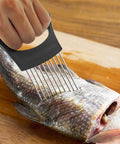 Onion slicer with holder, stainless steel prongs and black handle on a wooden cutting board