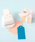 3-In-1 Round Tag Punch For Crafting And Scrapbooking, multi-color tool with gift tags and small wrapped gift box on pastel background
