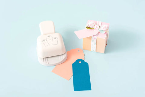 3-In-1 Round Tag Punch For Crafting And Scrapbooking, multi-color tool with gift tags and small wrapped gift box on pastel background
