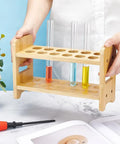 Person holding 12 Hole Test Tube Rack Made From Bamboo Wood Lab Stand For Chemistry Classrooms And Experiments, Features Interchangeable 26mm 27mm And 28mm Trays For Quick Organization And Sleek Display In The Lab.