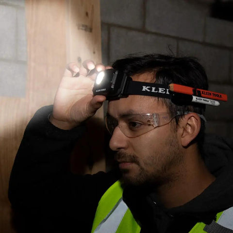 Person wearing a Rechargeable Two Color LED Headlamp With Durable Fabric Strap, illuminating a dark space, showcasing its spotlight mode.