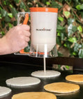 Using Outdoor Griddle Breakfast Prep Kit With Trigger Pancake Batter Dispenser to pour pancakes on a griddle.