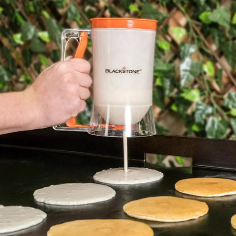 Using Outdoor Griddle Breakfast Prep Kit With Trigger Pancake Batter Dispenser to pour pancakes on a griddle.
