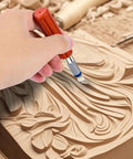 Hand using 13 Piece Precision Craft Knife Set with Interchangeable Blades and Ergonomic Handles for detailed wood carving.
