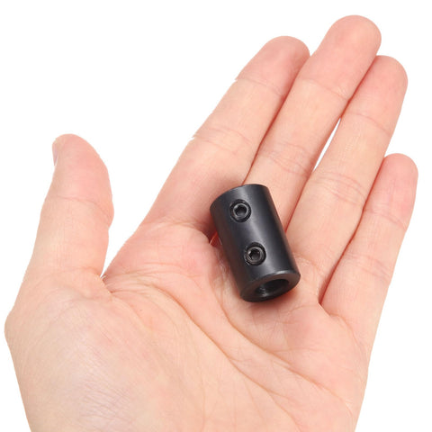 Hand holding Beefy Rigid Shaft Coupling With Set Screws Five Eighths Inch Bore One And A Quarter Inch Outside Diameter Two Inch Length Black