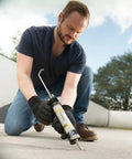 Man using Premium Textured Concrete Elastomeric Pro Grade Filler And Sealant 12 Pack to seal patio joints, weatherproof.