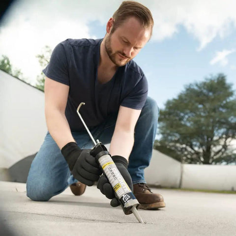 Man using Premium Textured Concrete Elastomeric Pro Grade Filler And Sealant 12 Pack to seal patio joints, weatherproof.